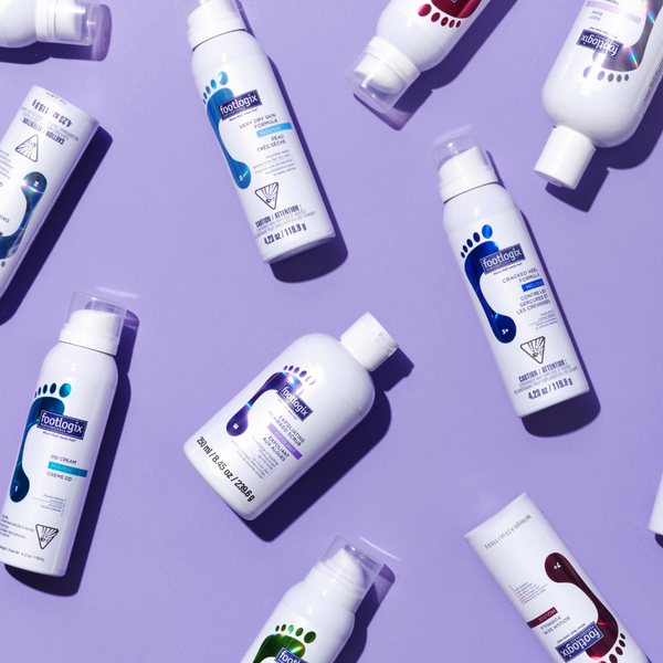 Flat lay of Footlogix professional foot care products on a lavender background, featuring various mousse formulas and lotions designed to treat dry, rough, and problem-prone feet.
